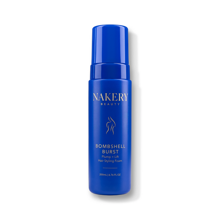A blue cylindrical pump bottle of NAKERY BEAUTY Bombshell Burst Pump + Lift Hair Styling Foam, shown on a clean white background with a soft shadow.